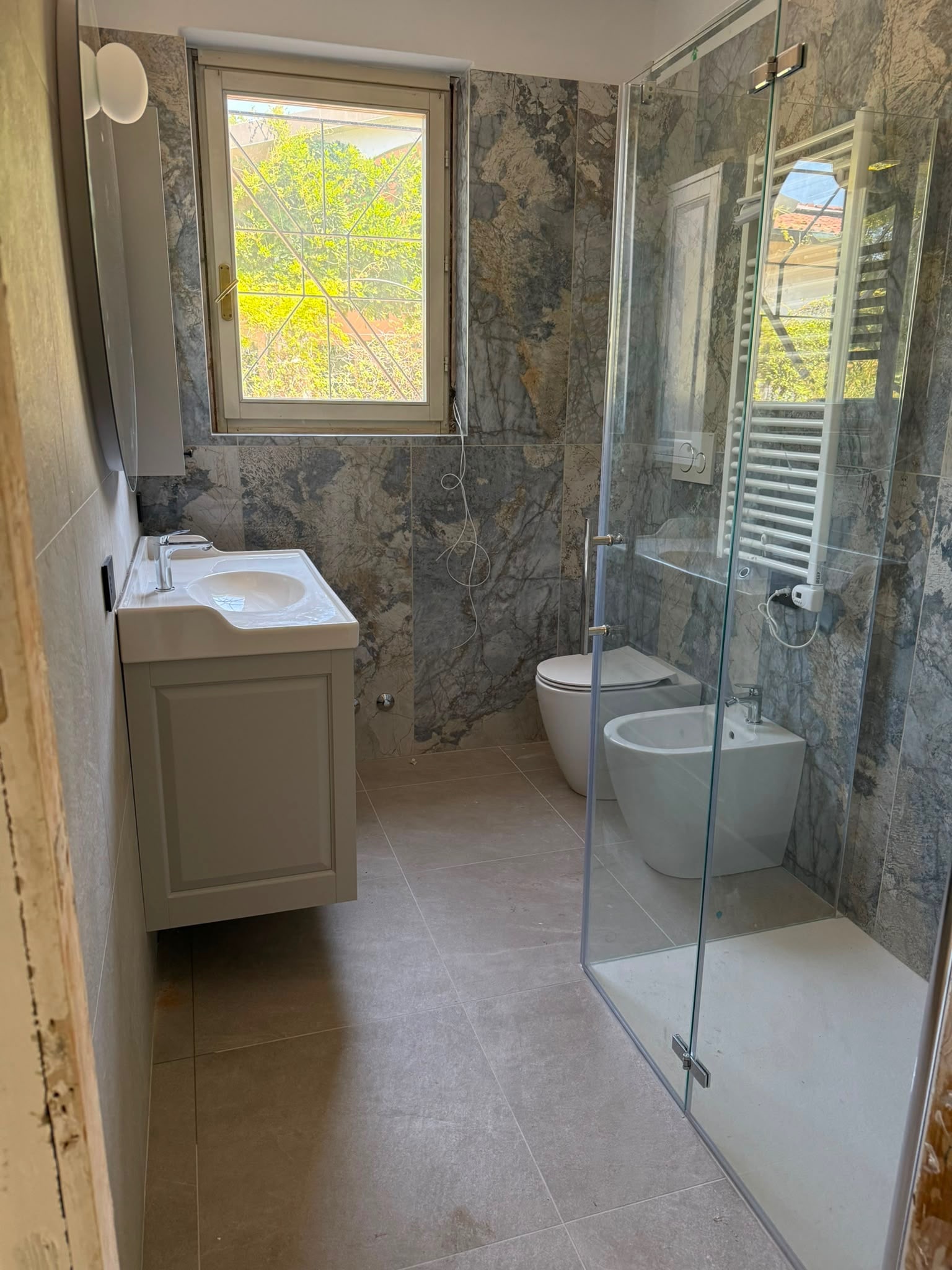 Bagno completato con doccia in vetro, sanitari e mobile lavabo